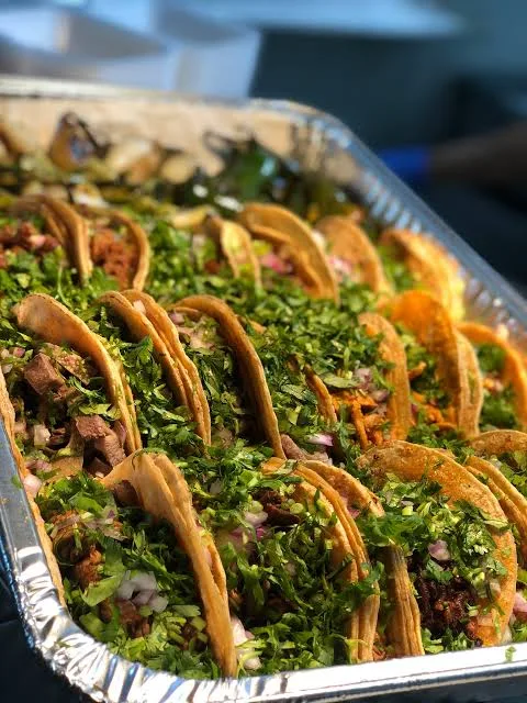 Tray of street tacos with cilantro and onion for a catered event by Delicias Factory